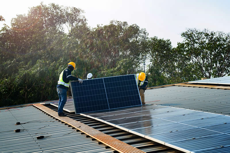 Technicians working on commercial business rooftop installing solar panels.